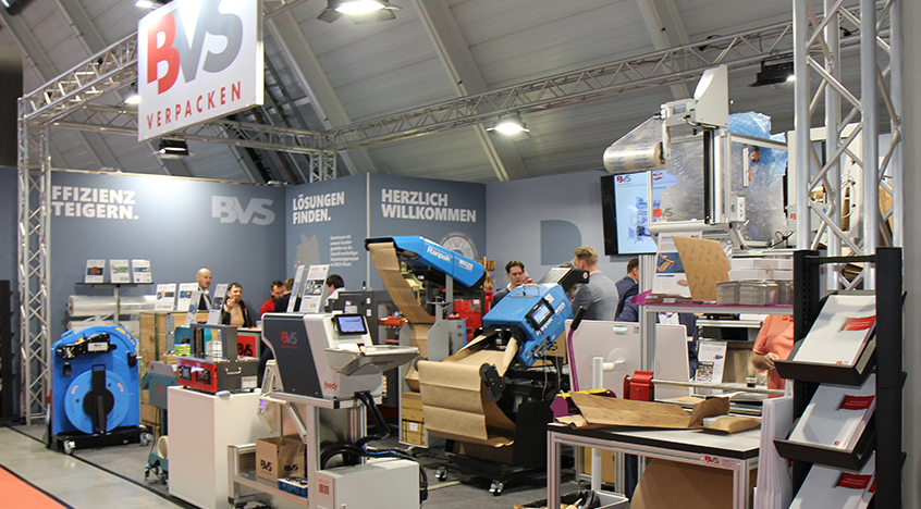Messestand von BVS Verpacken auf der LogiMAT mit laufenden Verpackungsanlagen und Besuchern im Gespräch